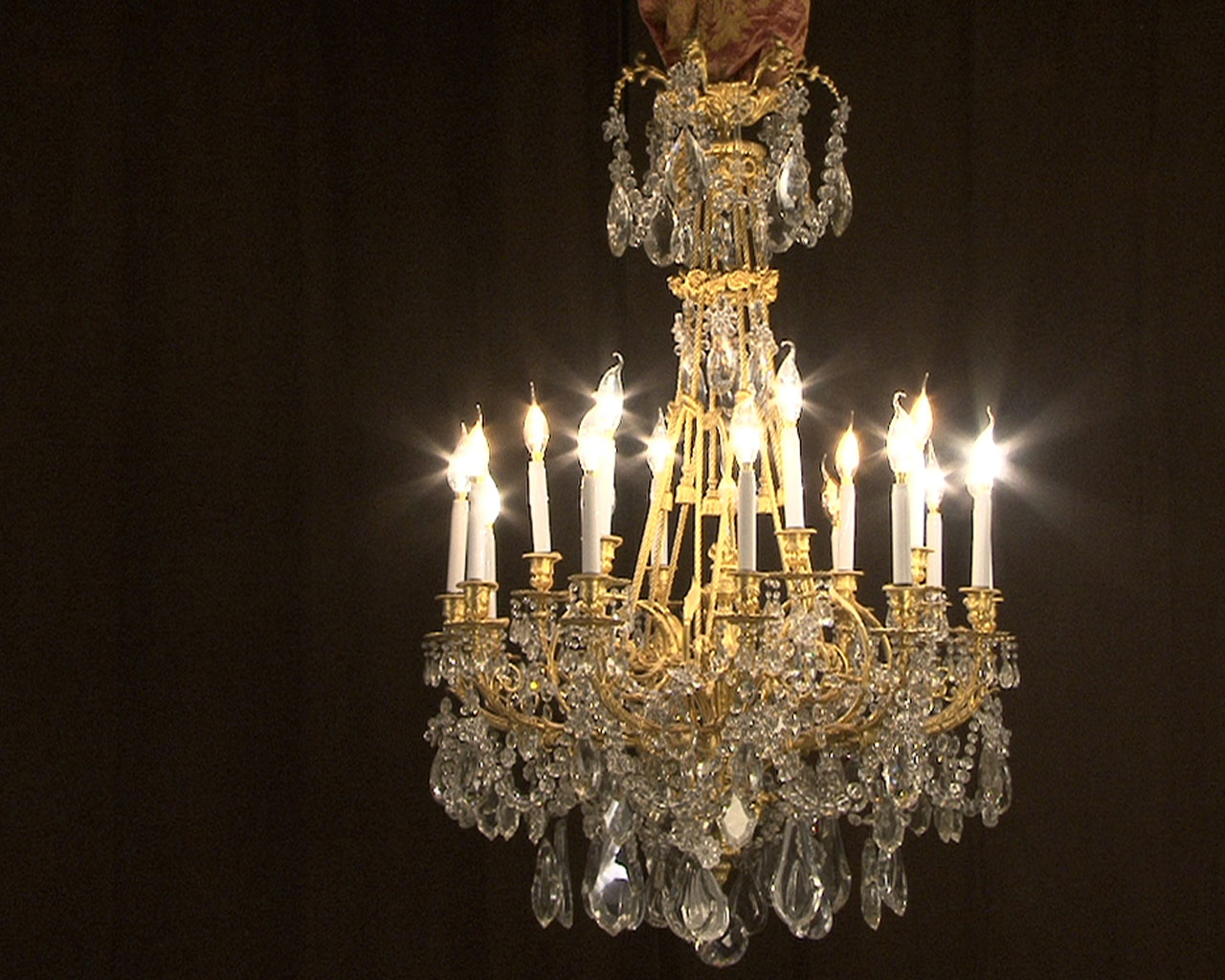 Lustre à cristaux à 12 bras et 18 lumières , décors de passementeries en bronze doré.-1