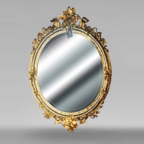 Miroir doré de forme ovale et de style Napoléon III, au riche décor végétal