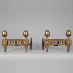 BOUHON: Paire de chenets de style Louis XVI en bronze doré aux pommes de pin stylisées