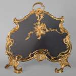 Pare étincelle de style Louis XV en bronze doré décoré d'instruments de musique