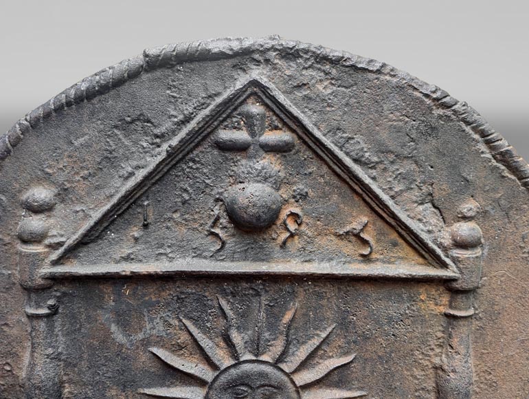 Plaque de cheminée en fonte datée 1693, décorée d’un soleil rayonnant et de symboles architecturaux-1