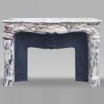 Cheminée de style Louis XV en Brèche Violette, au cartouche central encadré de palmettes